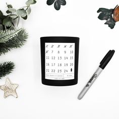 a desk with a calendar and pen on it next to some plants, scissors and other items