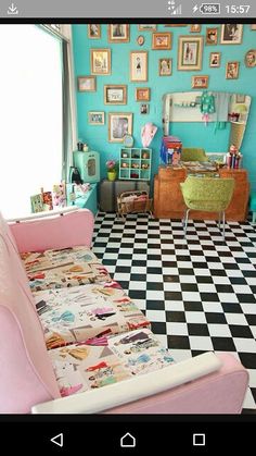 a pink couch sitting on top of a checkered floor in front of a blue wall