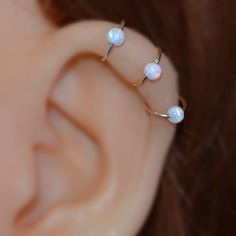 a close up of a person's ear with opal piercings