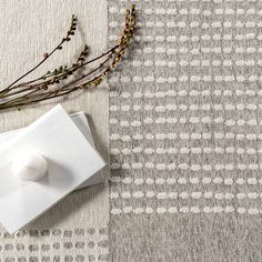 a white vase sitting on top of a table next to a piece of paper and flowers