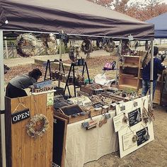 an outdoor flea market with people looking at items on display under a tent in the dirt