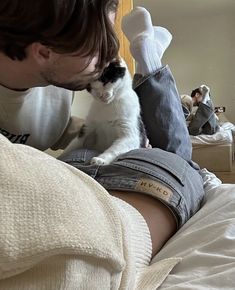 a man laying on top of a bed next to a black and white cat in his lap