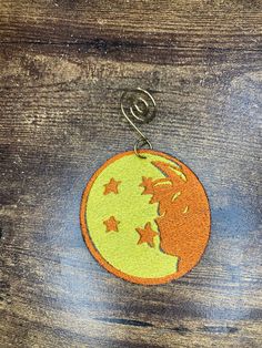 an orange and yellow moon with stars hanging from it's side on a wooden surface