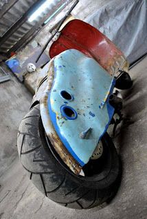 an old blue and red scooter sitting on the ground