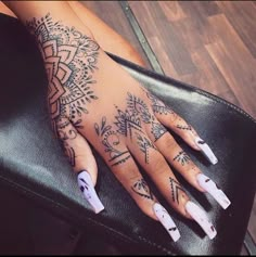 a woman's hand with black and white henna tattoos on her left arm