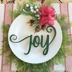 a white plate with the word joy written in green lettering on it and a red bow