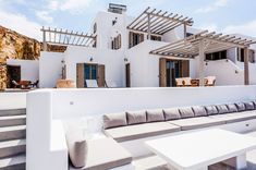 an outdoor seating area on the roof of a white house with stairs leading up to it