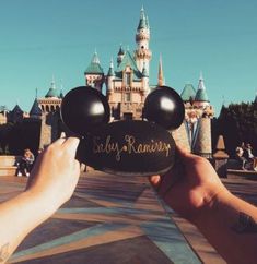 someone holding up a mickey mouse sign in front of a castle