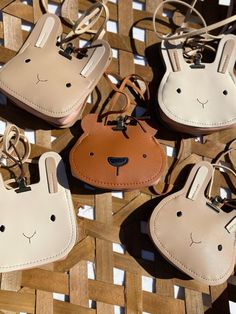 four small purses with faces on them sitting on top of a woven tablecloth