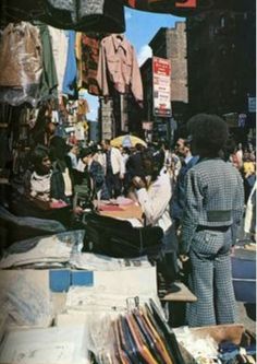 people are shopping in an outdoor market with clothes hanging from the ceiling and clothing on display