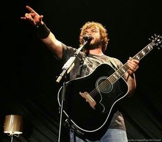 a man singing into a microphone while holding a guitar