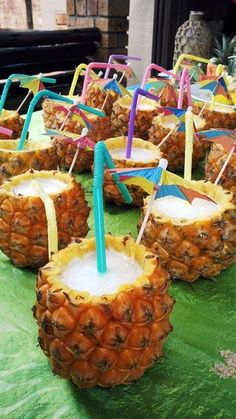 several pineapples with strawberries and umbrellas in them on a green tray