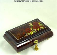 an ornate wooden box with flowers painted on the lid and tassels attached to it