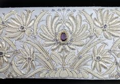 "Look absolutely stunning wearing this chic and ultra glamorous pale blue silk bridal clutch hand embroidered with a sparkly silver lotus flower pattern and embellished with a deep colored amethyst gemstone. Further studded with aqua chalcedony stone beads, sewn in. The lotus flower is the symbol of rebirth and new beginnings, as it emerges pure white from the waters in which it grows. Perfect symbol for a wedding! Something blue? Got it! Wear this on your special day and for years to come. This Elegant Evening Bag With Gold Embroidery For Reception, Designer White Evening Bag For Gift, Formal Embroidered Silver Evening Bag, Designer White Evening Bag As Gift, Gold Clutch With Intricate Embroidery For Wedding, Luxury Clutch With Gold Embroidery For Reception, Luxury Gold Embroidered Clutch For Reception, Gold Wedding Clutch With Intricate Embroidery, Designer Embellished Clutch For Wedding