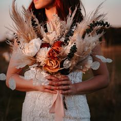 a woman in a white dress holding a bouquet with feathers on her chest and wearing a flower crown