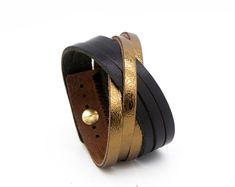 a black and gold leather bracelet on a white background