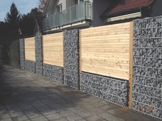 a row of stone and wood fences on the side of a building with balconies