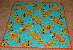 a blue and orange quilt on top of a floor next to a rug with an animal design