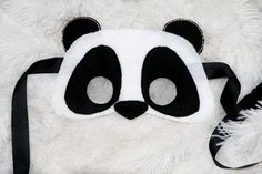 a panda bear mask on top of a white stuffed animal