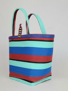 Material: Recycled plastic. Color: Red, blue, sky blue, black. Size: Height 12" Width 14" Use: Grocery, beach, pool... Property: Waterproof, easy to clean. Origin: West Africa. Handwoven bags made from recycled plastics. This bag is waterproof and very easy to clean. This material is very strong and can hold heavy contain.