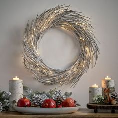 a christmas wreath on a wall next to candles and other holiday decorations with pomegranates