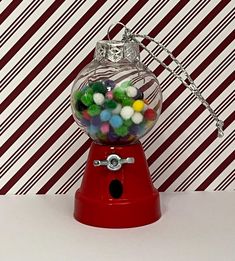 a red gummy machine sitting on top of a table next to a striped wall