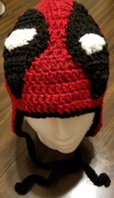 a red and black crocheted hat sitting on top of a white mannequin head