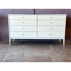 a white dresser sitting on top of a stone floor