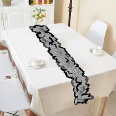 a white table with black lace on it and some chairs in front of the table