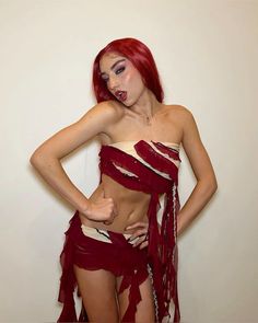 a woman with red hair and makeup is posing for the camera, wearing a costume