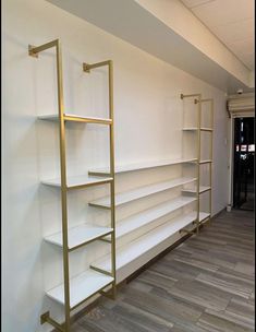 the empty shelves are lined up against the wall in this room with wood flooring