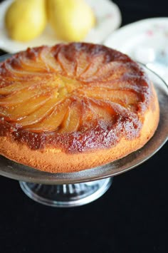 a pineapple upside down cake sitting on top of a glass plate next to two lemons