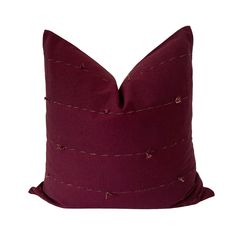 a purple pillow with small pins on the front and back, sitting on a white surface