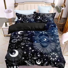 a bed covered in black and white sheets with stars, moon and planets on it