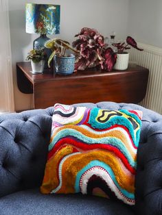 a blue couch with a colorful pillow on top of it next to a wooden table