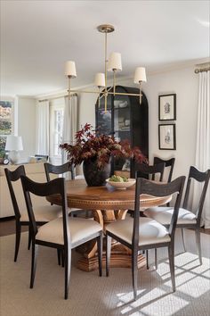 a dining room table with chairs and a vase filled with flowers on top of it