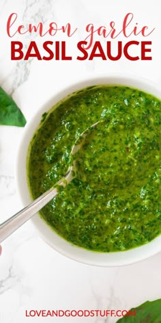 a white bowl filled with basil sauce on top of a marble counter next to green leaves