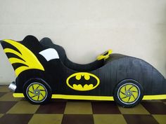 a black and yellow toy car with batman symbol on it's front wheel, sitting on a checkered floor