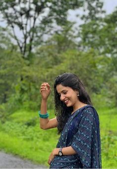 a woman standing on the side of a road holding her hand up in the air