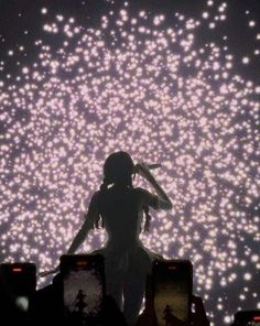 a woman standing in front of a large screen with lights on it's sides