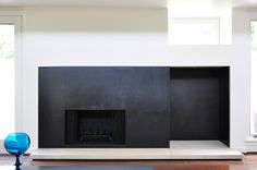 an empty living room with a fireplace in the center and two blue vases on the floor