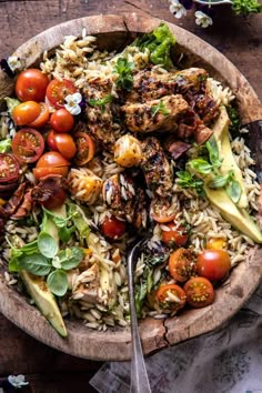 a wooden bowl filled with lots of food on top of a table next to a fork