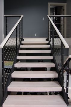 a set of stairs leading up to a second story room with gray walls and black railings