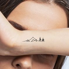 a woman's arm with trees and mountains tattoo on the left side of her arm