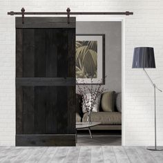 an open door leading to a living room with white brick walls and wood flooring