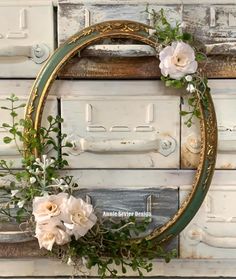 a wreath with white flowers and greenery hanging on the front door to an old wooden door