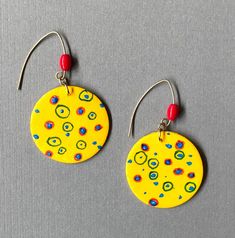 "Happy Bright  yellow with colored dots & circles, accented with a red glass bead, brass V wires. 1& 1/4\" diameter." Abstract Earrings, Polymer Earrings, Paper Jewelry, Pearl Earrings Dangle, Wooden Earrings, Red Glass, Jewelry Creation, Diy Earrings, Sunny Day