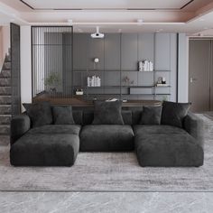 a large gray couch sitting in the middle of a living room next to a staircase