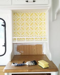 a yellow and white wallpaper is being painted on the back of a kitchen cabinet