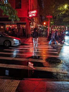 people crossing the street at night with red lights